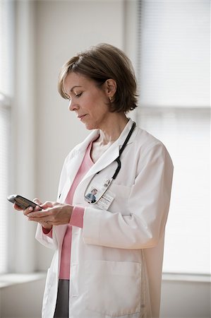 Doctor looking at cellphone Stock Photo - Premium Royalty-Free, Code: 614-02984110