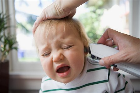 Adult putting thermometer in ear of crying baby Foto de stock - Royalty Free Premium, Número: 614-03020280