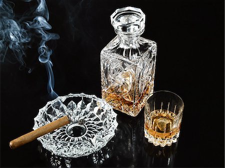 Cigar in ashtray with decanter and tumbler of whiskey Fotografie stock - Premium Royalty-Free, Codice: 614-03468711
