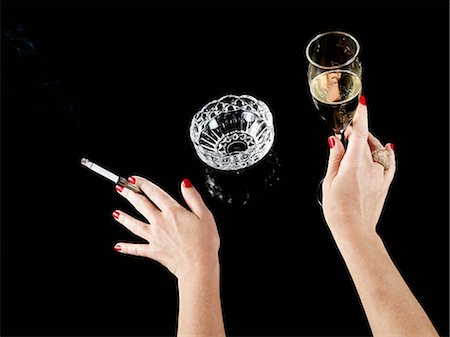 Female hand with cigarette in holder and glass of champagne Stock Photo - Premium Royalty-Free, Code: 614-03468740