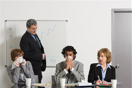 Businessman blowing nose in office Stock Photo - Premium Royalty-Free, Code: 614-03507042