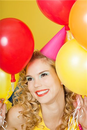 Young blonde woman with balloons against yellow background Stock Photo - Premium Royalty-Free, Code: 614-03507593
