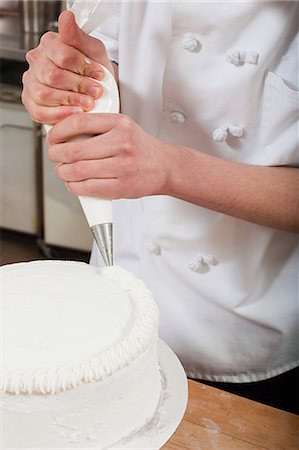 Female chef icing a cake Foto de stock - Royalty Free Premium, Número: 614-03551585