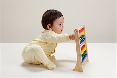 Baby boy playing with abacus Foto de stock - Royalty Free Premium, Número: 614-03576702