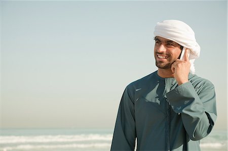 dubai men headdress - Middle Eastern man using mobile phone on the beach Stock Photo - Premium Royalty-Free, Code: 614-03577114