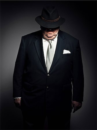 fat 60 year old man - Studio portrait of gangster with hat covering face Stock Photo - Premium Royalty-Free, Code: 614-03647854