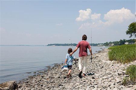 Father and son walking along beach with fishing rods Stock Photo - Premium Royalty-Free, Code: 614-03647949