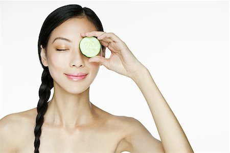 Woman holding cucumber over eye Foto de stock - Sin royalties Premium, Código: 614-03649503