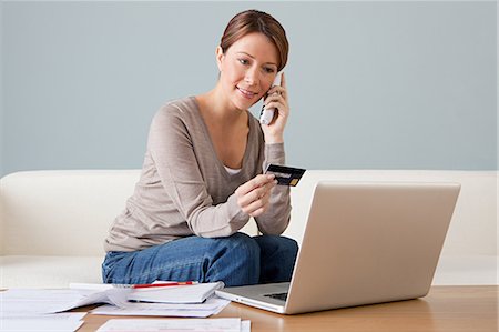 Jeune femme au téléphone avec ordinateur portable Photographie de stock - Premium Libres de Droits, Code: 614-03697150