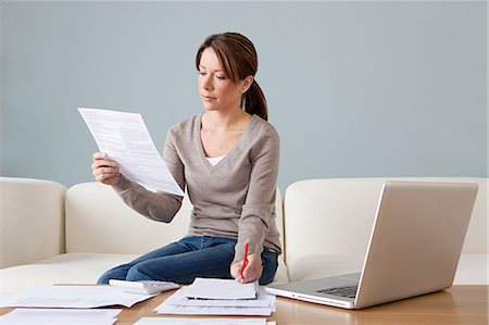 personal finance - Young woman with paperwork using laptop Stock Photo - Premium Royalty-Free, Code: 614-03697168