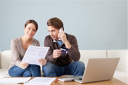 person on phone with a credit card - Young couple using computer and doing paperwork Stock Photo - Premium Royalty-Free, Code: 614-03697203