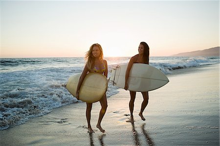 summer surfing adult - Female surfers by the sea at sunset Stock Photo - Premium Royalty-Free, Code: 614-03697636