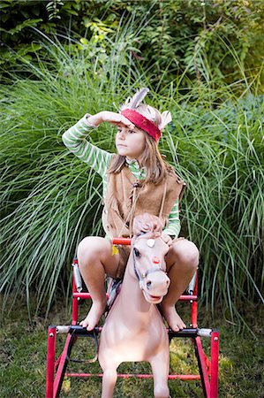 dressing up as a girl photos - Girl in Native American costume on rocking horse Stock Photo - Premium Royalty-Free, Code: 614-03747823