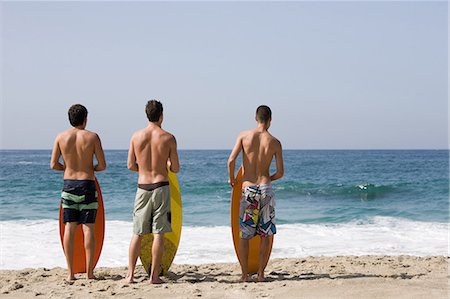 Three young men on beach with surfboards Stock Photo - Premium Royalty-Free, Code: 614-03763903