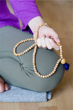 Woman kneeling holding beads Stock Photo - Premium Royalty-Free, Code: 614-03784044