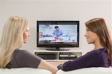 Two young women watching television Stock Photo - Premium Royalty-Free, Code: 614-03784131