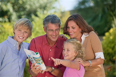 Family looking at guidebook and pointing Fotografie stock - Premium Royalty-Free, Codice: 614-03783477