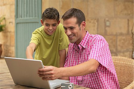 Father and son looking at laptop outdoors Stock Photo - Premium Royalty-Free, Code: 614-03783494