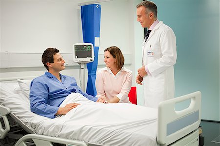 patient happy hospital - Wife visiting husband in hospital, talking to doctor Stock Photo - Premium Royalty-Free, Code: 614-03783641