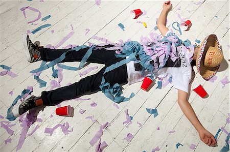 Man lying on floorboard covered with streamers at party Stock Photo - Premium Royalty-Free, Code: 614-03818467