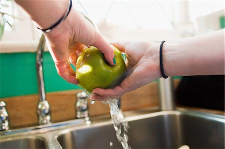 safety home - Teenage girl washing apple in kitchen sink Stock Photo - Premium Royalty-Free, Code: 614-03902783