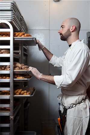 Butcher with racks of sausages on trays Fotografie stock - Premium Royalty-Free, Codice: 614-03903570