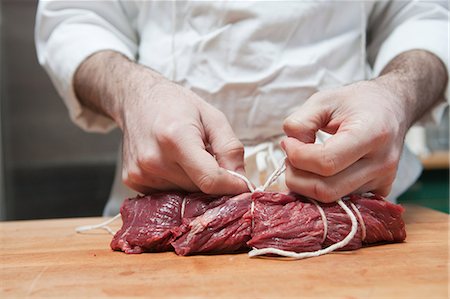 Butcher tying beef tenderloin with string Fotografie stock - Premium Royalty-Free, Codice: 614-03903591