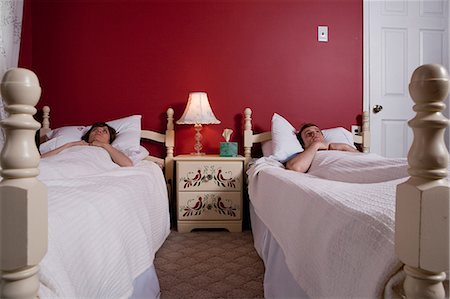 Young couple lying awake in single beds Stock Photo - Premium Royalty-Free, Code: 614-03981504