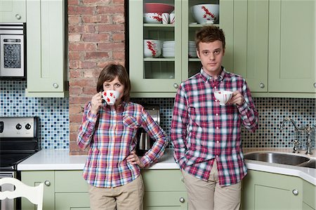 Young couple holding teacups in kitchen Foto de stock - Sin royalties Premium, Código: 614-03981542