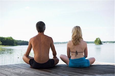 simsearch:6102-03751079,k - A man and a woman sitting on a bridge with their legs crossed, rear view. Foto de stock - Royalty Free Premium, Número: 6102-03748657