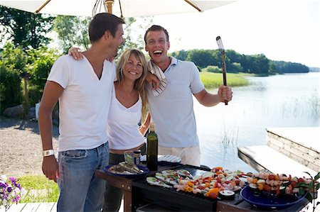 simsearch:6102-03828936,k - Deux hommes et une femme debout à l'aide d'une grille, en riant. Photographie de stock - Premium Libres de Droits, Code: 6102-03748682