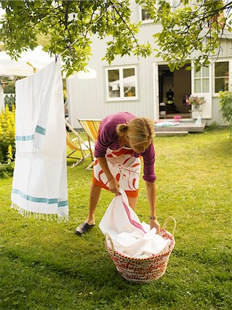 simsearch:6102-03828000,k - Woman hanging laundry in a garden. Foto de stock - Sin royalties Premium, Código: 6102-03749754