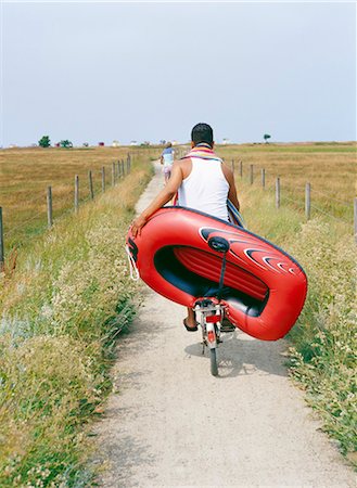 A man cykling carrying a rubber dinghy. Stock Photo - Premium Royalty-Free, Code: 6102-03749854