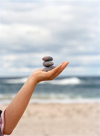 simsearch:6102-06777428,k - A hand holding up stones with the ocean in the background. Stock Photo - Premium Royalty-Free, Code: 6102-03750369