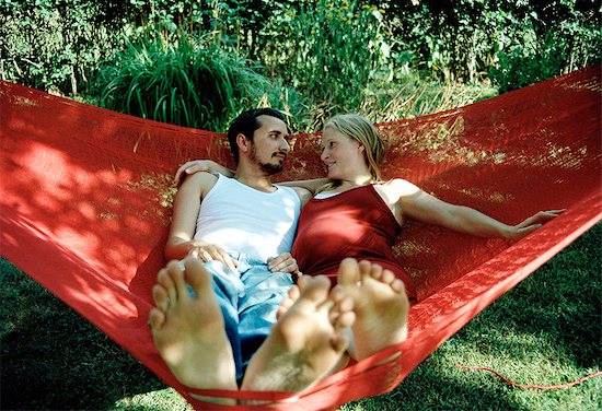 A young couple sitting in a hammock. Stock Photo - Premium Royalty-Free, Image code: 6102-03750421