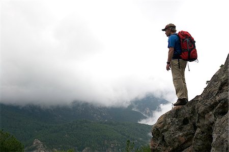 dizzy - A man standing on a ledge in a rock face among clouds. Stock Photo - Premium Royalty-Free, Code: 6102-03750971