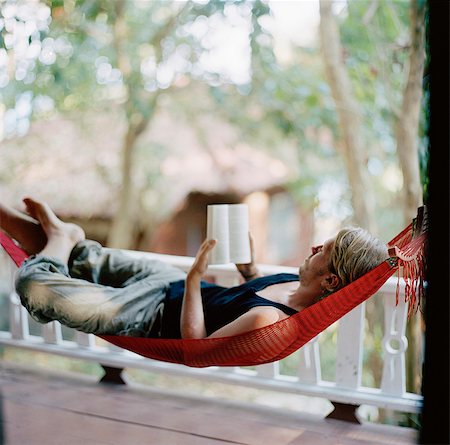A young man in a hammock, reading a book, Thailand. Stock Photo - Premium Royalty-Free, Code: 6102-03751064