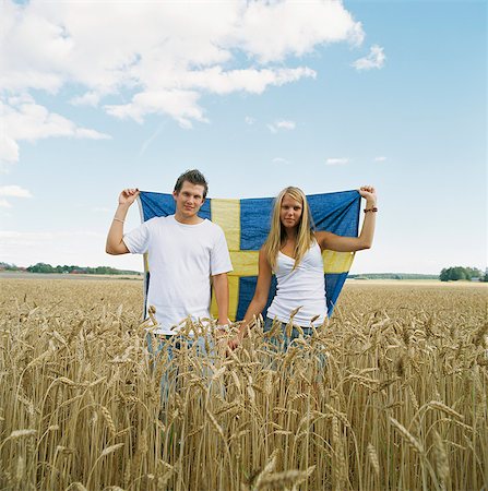 simsearch:6102-08271612,k - Portrait d'un jeune couple tenant le drapeau suédois, debout dans le champ de blé Photographie de stock - Premium Libres de Droits, Code: 6102-03859279