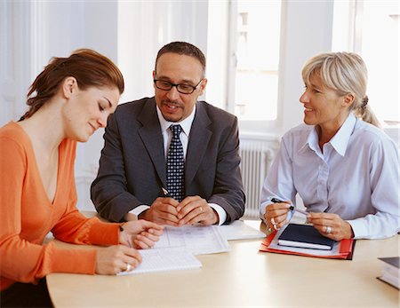 Businessman and women sitting at desk having discussion, smiling Stock Photo - Premium Royalty-Free, Code: 6102-03859225