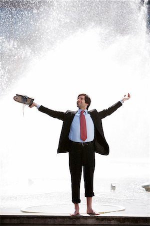 Businessman standing next to a fountain, Stockholm, Sweden. Stock Photo - Premium Royalty-Free, Code: 6102-03865708