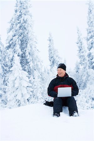 A man with a laptop in a forest a winter day, Sweden. Stock Photo - Premium Royalty-Free, Code: 6102-03866436
