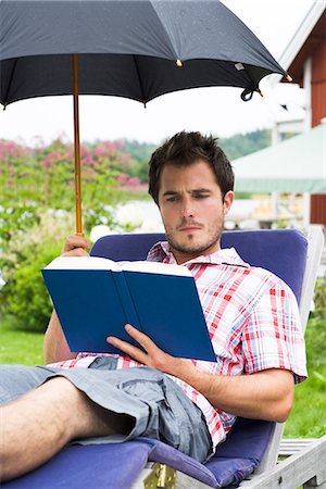 simsearch:6102-03866911,k - A man with an umbrella sitting in a sun chair reading a book, Sweden. Stock Photo - Premium Royalty-Free, Code: 6102-03866791