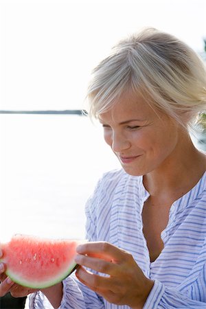 A woman eating a watermelon by the sea in the archipelago of Stockholm, Sweden. Stock Photo - Premium Royalty-Free, Code: 6102-03866864