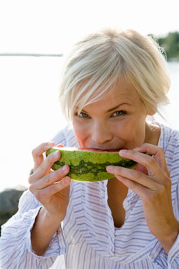 A woman eating a watermelon by the sea in the archipelago of Stockholm, Sweden. Foto de stock - Sin royalties Premium, Código de la imagen: 6102-03866866