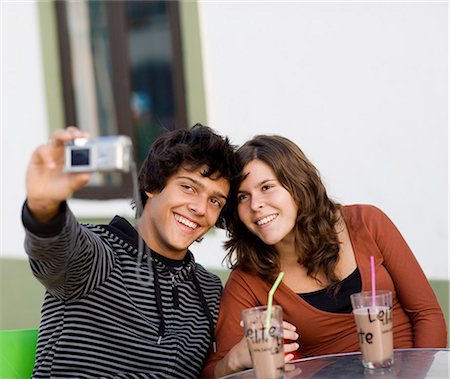 A young couple sitting at a cafe holding a camera, Portugal. Stock Photo - Premium Royalty-Free, Code: 6102-03867357