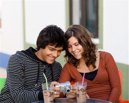 A young couple sitting at a cafe holding a camera, Portugal. Foto de stock - Sin royalties Premium, Código: 6102-03867358