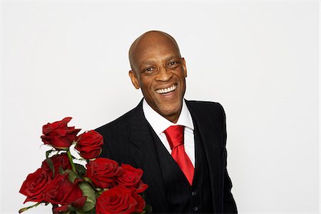 simsearch:6102-03905315,k - A man wearing a suit and holding a buncht of red roses Foto de stock - Sin royalties Premium, Código: 6102-03826824