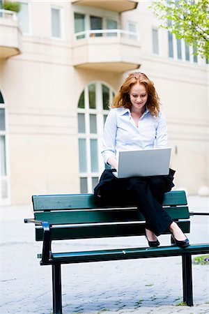 Woman sitting on a bench using her laptop, Stockholm, Sweden. Stock Photo - Premium Royalty-Free, Code: 6102-03827452