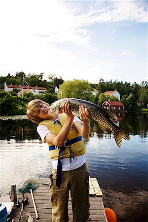 A boy with a fish on a jetty, Sweden. Stock Photo - Premium Royalty-Free, Code: 6102-03827769
