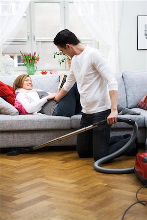 pregnant couple couch - Une femme enceinte, couché sur un divan et un homme, passer l'aspirateur, Suède. Photographie de stock - Premium Libres de Droits, Code: 6102-03827878